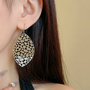 Detail view of elegant silver hollow metal leaf earrings on a female model
