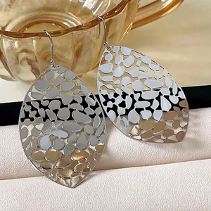 Close-up detail of silver hollow leaf metal drop earrings with geometric pattern