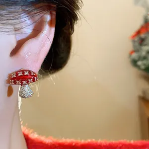 Close-up detail of a red enamel mushroom earring with zircon stones on an ear.