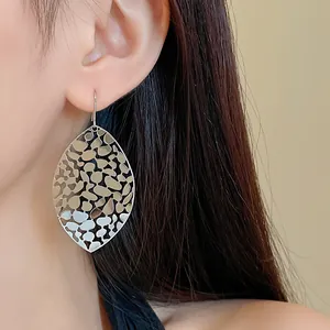Detailed macro shot of silver hollow leaf earrings featuring an intricate geometric pattern