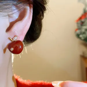 Close-up detail of a red oil-dripped apple stud earring with sparkling zirconia stones.
