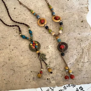 Detailed view of handcrafted ceramic and wooden bead necklaces with leaf tassel accents