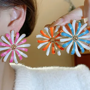 Detailed view of three colorful enamel daisy stud earrings in pink, orange, and blue.