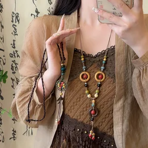 Macro view of retro ceramic and wooden bead necklace featuring unique tassel detail and leaf pendant
