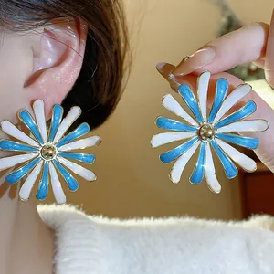 Detailed view of stylish blue and white enamel flower stud earrings worn on ear