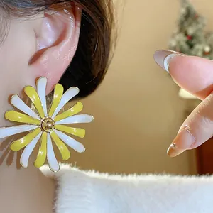Detailed close-up showing a yellow and white enamel flower stud earring worn on an ear