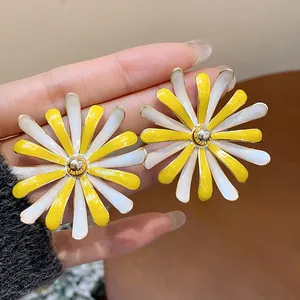 Close-up detail of large yellow and white enamel daisy flower stud earrings for women