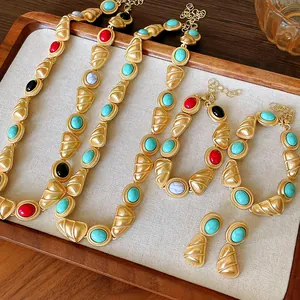 Détail d'une parure de bijoux vintage avec maillons dorés mats et pierres turquoise