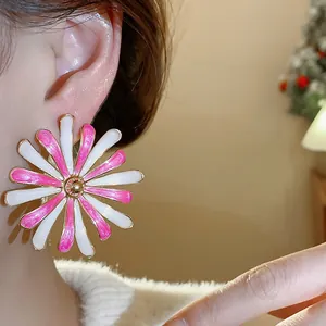 Close-up of large pink and white enamel daisy flower stud earring on model's ear.