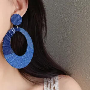 Close-up of vintage denim fabric oval cutout earrings worn on ear for detail