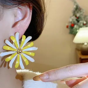 Close-up view of a large yellow and white daisy flower stud earring worn on the ear