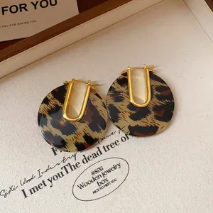 Detailed shot of leopard print acetate U-shaped hoop earrings with 18k gold plating.