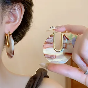 Detailed macro view of vintage U-shaped earrings with 18k gold plating and acetate patterns