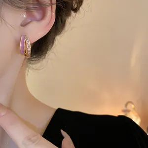 Detailed close-up of elegant gold-plated geometric hoop earrings with purple enamel and CZ stones