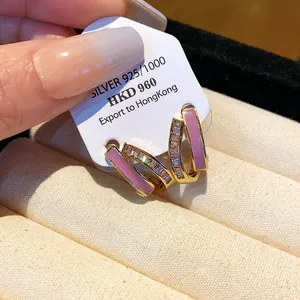 Detailed view of gold-plated silver earrings with pink enamel and sparkling zircon