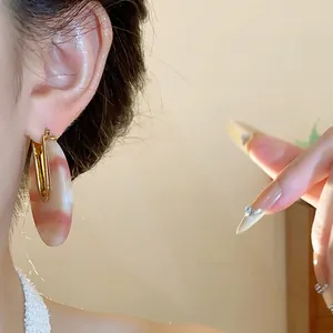 Detail view of U-shaped 18k gold plated earring with pink marble acetate drop jewelry