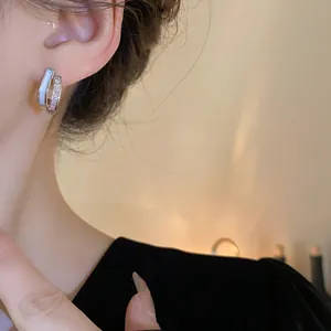 Close-up detail of geometric silver needle earrings with shimmering zircon stones and shell inlay
