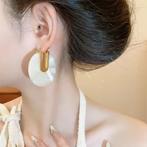 Close-up detail showing elegant 18k gold plated U-shaped earrings with marble acetate disks