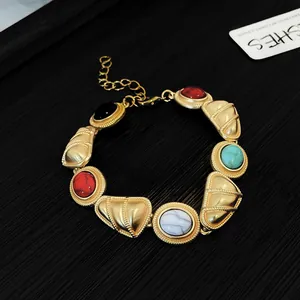 Détail d'un collier doré vintage de style cour avec incrustations de pierres colorées.