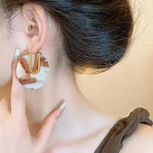 Macro detail of retro 18k gold plated U-shaped earrings with brown marble acetate disc