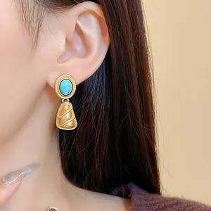 Gros plan de boucles d'oreilles vintage dorées avec pierre turquoise sur mannequin