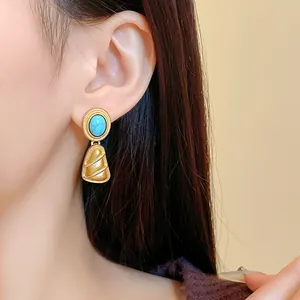 Vue détaillée de boucles d'oreilles pendantes vintage dorées avec pierre turquoise