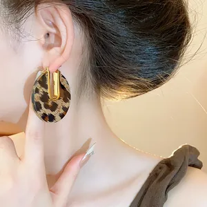 Close-up of leopard print acetate U-shaped earrings on a model, 18k gold plated.