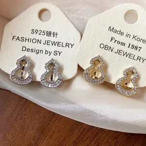 Detailed view of gold and silver gourd-shaped clip-on earrings with pavé zircons