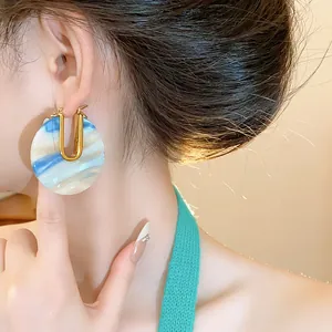 Macro detail of 18k gold plated U-shaped hoop earrings with blue marble acetate