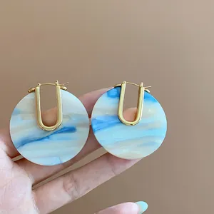Macro view of blue marble acetate U-shape hoop earrings with premium 18k gold plating
