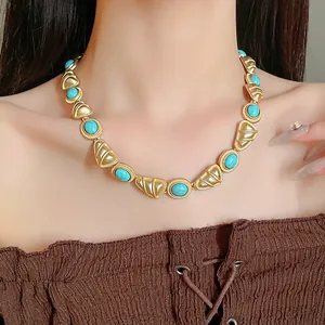 Gros plan d'un collier en or vintage avec des pierres turquoise porté par un mannequin.