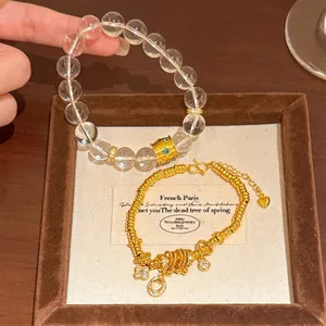 Detailed view of elegant gold-tone beaded bracelet with flower charms and clear beads.