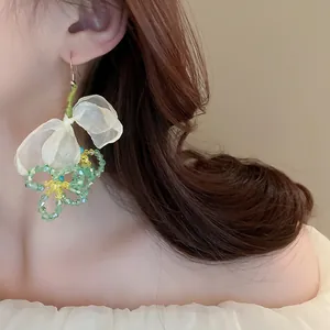 Vue détaillée de boucles d'oreilles faites main avec nœud en maille et perles vertes