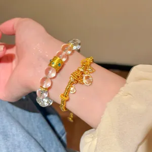 Close-up of gold-toned zircon flower bracelet and beaded hand jewelry on wrist