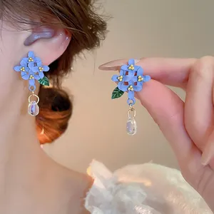 Vue macro détaillée montrant un mannequin portant d'élégantes boucles d'oreilles fleurs bleues
