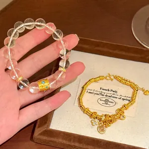Close-up detail of luxury gold beaded bracelet with flower charms and clear quartz beads