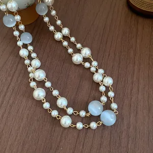 Detailansicht einer vintage mehrlagigen Kette mit Perlen und Katzenaugenstein auf Holz.