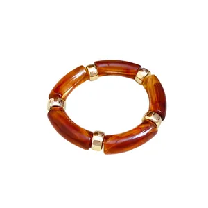 Pulsera retro de acrílico con efecto carey y cuentas doradas sobre fondo blanco puro.