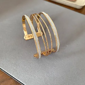 Close-up of multi-layer gold cuff bracelet with glitter and polished finish