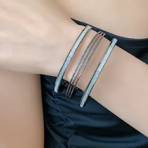 Elegant macro detail of multi-layer metal glitter bangle set worn on a model's wrist
