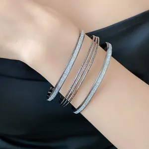 Detailed view of elegant multi-layered silver glitter open bangles on a woman's wrist