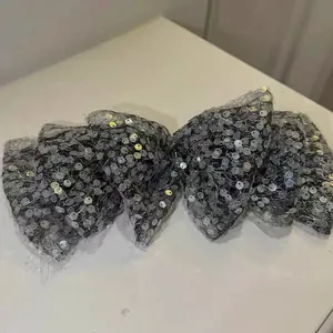 Detailansicht einer grauen Netz-Haarschleife mit glänzenden silbernen Pailletten.