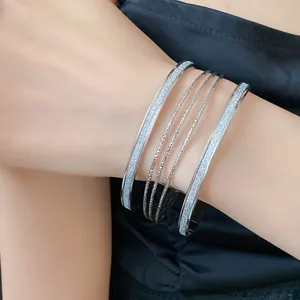 Detailed macro view of stylish multilayer silver glitter open cuff bracelets on model wrist