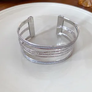 Detail view of a multi-layer silver metallic cuff bracelet with glitter and textured bands.