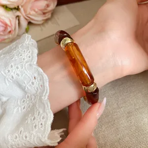 Primer plano de pulsera de acrílico ámbar carey con espaciatori dorados en la muñeca