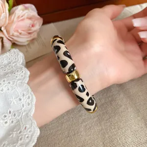 Elegante pulsera de acrílico con estampado de leopardo y detalles dorados en la muñeca