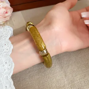 Primer plano de pulsera de acrílico con purpurina dorada en muñeca con encaje
