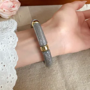 Vista detallada de una pulsera de acrílico plateada brillante con elegantes toques de oro