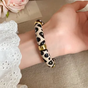 Detalle de pulsera retro de acrílico con estampado de leopardo y toques dorados