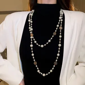 Detaillierte Nahaufnahme einer langen Perlenkette mit goldenen Rosen-Zwischenstücken am Model